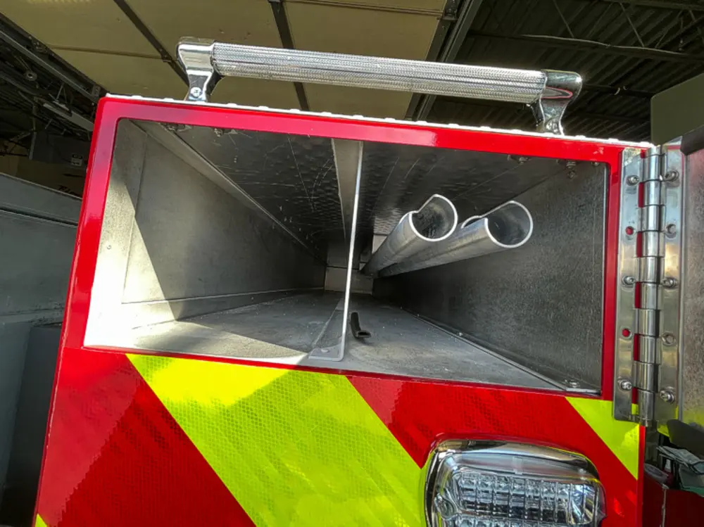 Exterior view of small fire truck showing cab, body compartments, and wheel/tire area.